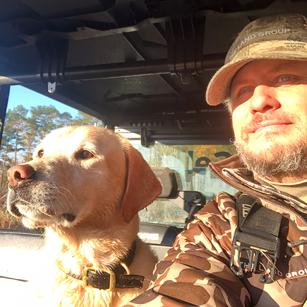 a man driving a car with a dog in his lap