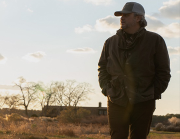 a man standing in a field with a dog
