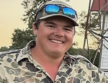 a man wearing a camo shirt and sunglasses