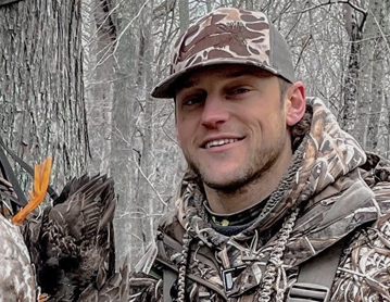 a man holding a bird in the woods