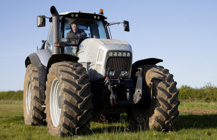 a man driving a tractor across a lush green field