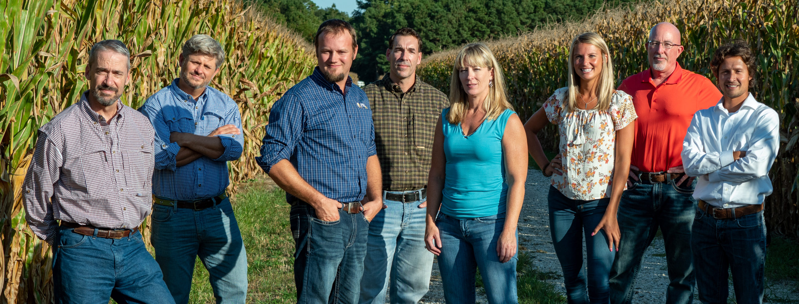 a group of people standing in front of a corn field