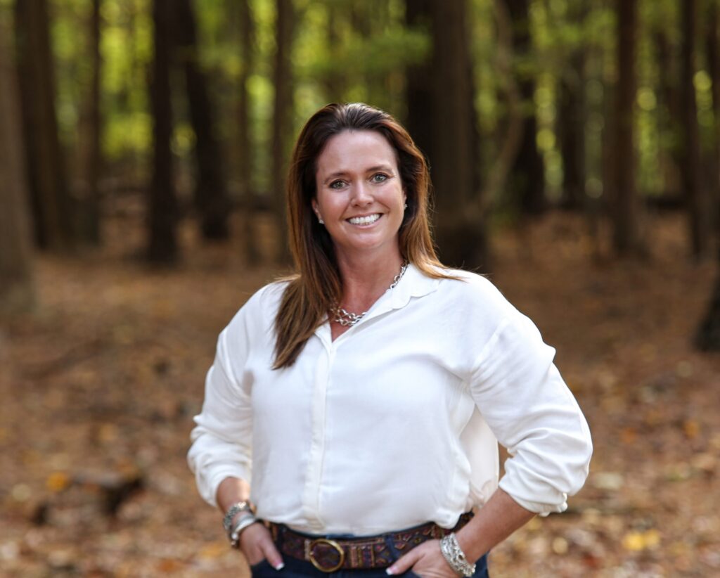 a woman standing in the woods with her hands on her hips