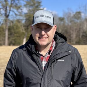 a man standing in a field wearing a hat