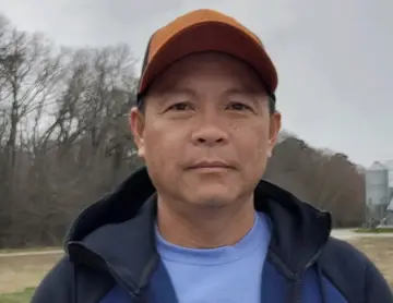 a man in a blue shirt and a brown hat